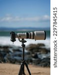 A vertical closeup of surf photography telephoto lens and camera body on tripod. Jeffreys Bay, Africa.