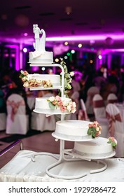 A Vertical Closeup Of A Unique Wedding Cake With A Tiny Bride And Grom And Flowers