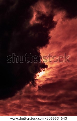 Vertical cloudy landscape with an overhanging thundercloud at sunset day in autumn. Selective focus.