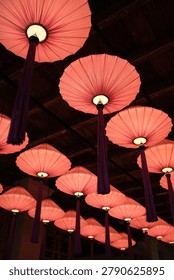 Vertical Composition of Decorative Hanging Lanterns. Vertical view of colorful lanterns suspended from a traditional wooden ceiling. Suitable for culture, hospitality and interior design themes.