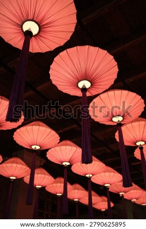 Vertical Composition of Decorative Hanging Lanterns. Vertical view of colorful lanterns suspended from a traditional wooden ceiling. Suitable for culture, hospitality and interior design themes.