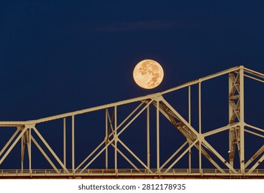 Vertical composition of the full moon dropping behind the steel trusses of the Second Street Bridge in Louisville during a fall 2025 sunrise.