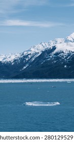 Vertical composition highlighting the dramatic contrast between icy waters and snow-covered mountains near Hubbard Glacier.