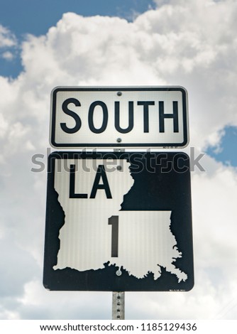 A vertical composition of a Louisiana highway 1 south roadside sign post