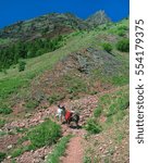 Vertical composition of a man and his llama stopped on a high alpine mountain trail at a switchback. The man and his llama are packing into the beautiful Bob Marshall Wilderness.