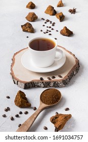 Vertical composition of organic Chaga mushrooms and coffee on light background. Trendy healthy beverage.