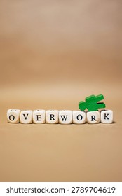 Vertical composition with the word OVERWORK and a fallen green human figure. Concept of employee burnout, work related stress, emotional exhaustion and mental health challenges in the workplace.