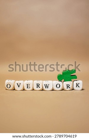 Vertical composition with the word OVERWORK and a fallen green human figure. Concept of employee burnout, work related stress, emotional exhaustion and mental health challenges in the workplace.