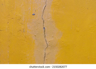 Vertical Crack On The Wall. Yellow Wall Of The Building With A Vertical Crack And Bad Fix.