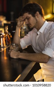 Vertical Cropped Portrait Of A Handsome Young Man Looking Tired And Upset Drinking Whiskey Alone At The Bar Rubbing His Forehead Stress Depression Depressed Unhappy Exhausted Overworking