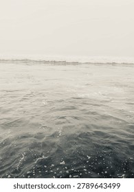 A vertical, dramatic black and white shot of ocean surf rolling in after a fog bank has passed in Carlsbad, California