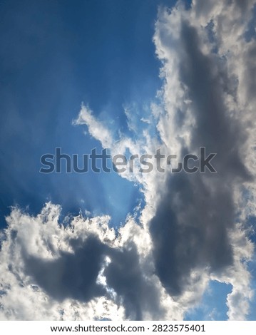 Vertical dramatic blue sky with dark storm clouds, crepuscular sun rays and striking natural cloudscape background.