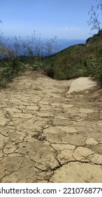 Vertical, Dry Cracked Path Ground In Mountains. Grass On Background. Global Warming, Summer Without Rain And Water. Textures Of Ground.