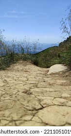 Vertical, Dry Cracked Path Ground In Mountains. Grass On Background. Global Warming, Summer Without Rain And Water. Textures Of Ground.