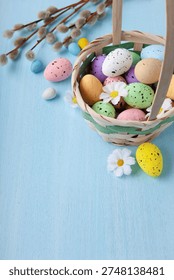 Vertical Easter greeting with painted egg in wicker basket and pussywillow branch arranged for elegant spring holiday celebration card design