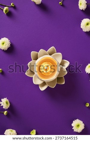 Vertical flat lay of burning lotus surrounded by white flowers, symbols of purity for Vesak Day.