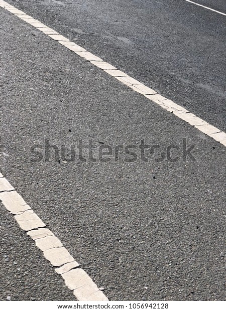 Vertical format, closeup of asphalt road, white\
painted lane dividers