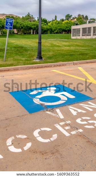 Vertical frame Handicapped parking lot\
with painted handicap symbol and Van Accessible\
sign