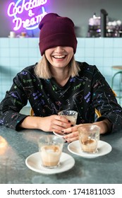 Vertical Frame Young Hipster Female Teenager Sitting At Counter In Front Of Several Half-empty Cups Of Coffee, Laughingly Pulled A Beanie Hat Over Her Eyes. Stress Management