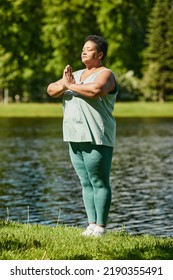 Vertical Full Length Portrait Of Mature Black Woman Meditating In Sunlight While Enjoying Yoga Session Outdoors