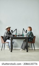 Vertical Full Length Portrait Of Two People Speaking To Microphones While Recording Podcast In Studio