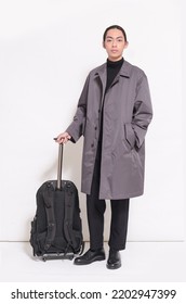 Vertical Full Length Studio Shot Of
 Portrait Of Confident Young Man In Stylish Long Coat  With Holding Hand Luggage Standing In Studio 
