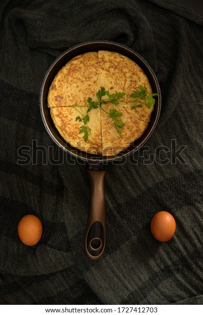 A vertical\
high angle closeup shot of an omelet divided into four pieces in a\
roaster and two eggs on the\
sides