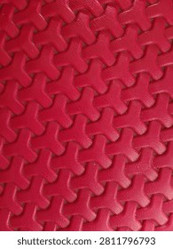 vertical high angle shot of a vibrant red non slip plastic floor mat with an interlocking tri lobed textured pattern for modern abstract background designs