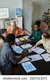 Vertical High Angle View Of Creative Business Team At Meeting Table Discussing Project