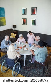 Vertical High Angle View At Diverse Group Of Senior People Enjoying Breakfast At Dining Table In Nursing Home, Copy Space