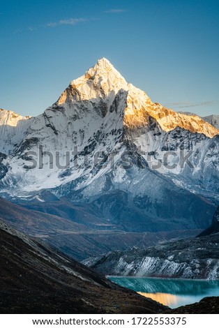Vertical image of Amadablam mountain peak during sunset and a view of Cholatse glacial lake on the foothills of mountains in Everest region of Nepal.