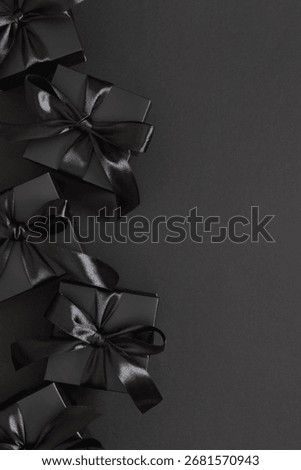 Vertical image of black gift boxes tied with a satin ribbon on a black background, conveying the festive spirit of Black Friday.