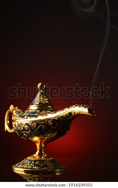 A vertical image of a brass\
magical Genie oil lamp with a smoke trail coming out of the\
spout.