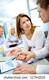 Vertical Image Of Business Partners Discussing Document With Their Colleagues Working On Background