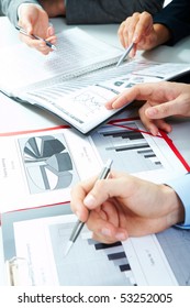 Vertical Image Of Business Partners Hands Over Papers Discussing Them