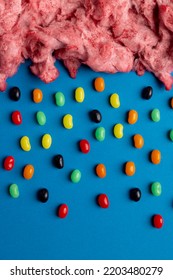 Vertical Image Of Cloud Of Homemade Pink Candy Floss Raining Jelly Beans, On Blue With Copy Space. Tasty Home Made Sweet Foods.