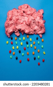 Vertical Image Of Cloud Of Homemade Pink Candy Floss Raining Jelly Beans, On Blue With Copy Space. Tasty Home Made Sweet Foods.