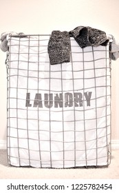 Vertical Image Of A Dirty Laundry Hamper With Clothing Hanging Out Of The Basket