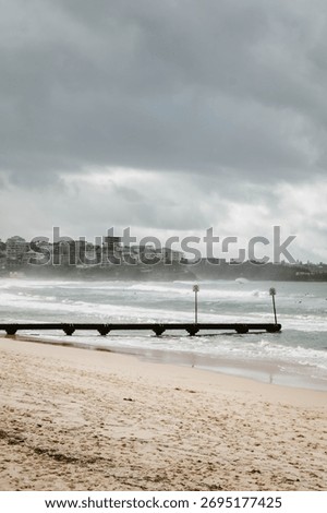 Vertical image of the empty beach at Manly Beach outdoor at daytime during a storm in the winter of Australia with cloudy sky and space for text.