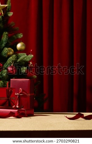 A vertical image featuring a Christmas tree and red gifts set against a rich red curtain. The elegant combination of colors creates a luxurious holiday backdrop.
