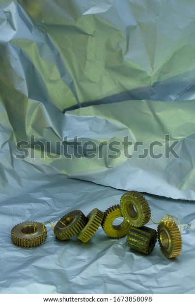 Vertical image.Lot\
of gears on the grey crumpled surface.Concept of metalwork and\
innovations, discovery