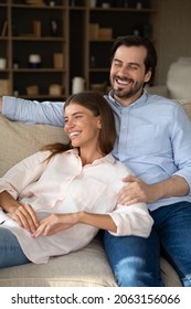 Vertical image happy laughing sincere loving affectionate married couple resting together on cozy couch, enjoying carefree leisure weekend time together in own house, good family relations concept.