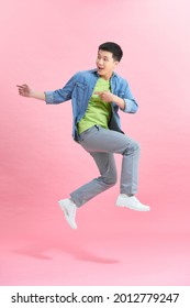 Vertical image of happy man jumping in studio  over pink background