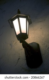 Vertical Image Of A Lit Porch Light In The Evening