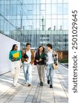 Vertical image of multiracial happy university students walking to class together laughing and talking. Group of young people in college campus. Higher education concept.