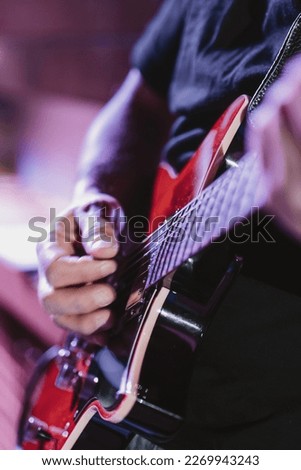 Vertical image of a musician playing the electric guitar during a concert, no faces are shown, close up look, shallow depth of field