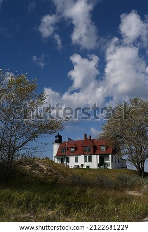 Vertical image of Point Betsie lighthouse on a summer day with clouds against a blue sky
