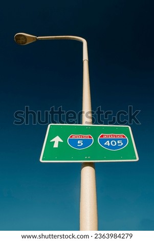 Vertical image of a roadsign for the Interstsate 5 and Interstate 405 freeways on a lightpole against a blue sky