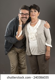 Vertical Image Of A Senior Adult Woman And Her Son Over Gray Background.