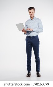 Vertical image of Smiling business man which standing in studio with laptop in hand and looking at camera. Isolated white background